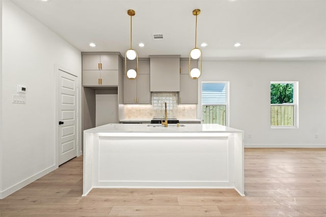 420 N Moore St, Dallas, TX 75203 - kitchen with gray cabinetry, tasteful backsplash, light wood-style flooring, a kitchen island with sink, and recessed lighting