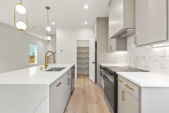 420 N Moore St, Dallas, TX 75203 - kitchen featuring wall chimney range hood, electric range oven, a center island with sink, light wood-style floors, and tasteful backsplash