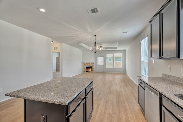 529 Mesa View Trl, Fort Worth, TX 76131 - kitchen featuring dishwasher, light wood finished floors, a raised ceiling, light stone counters, and a center island