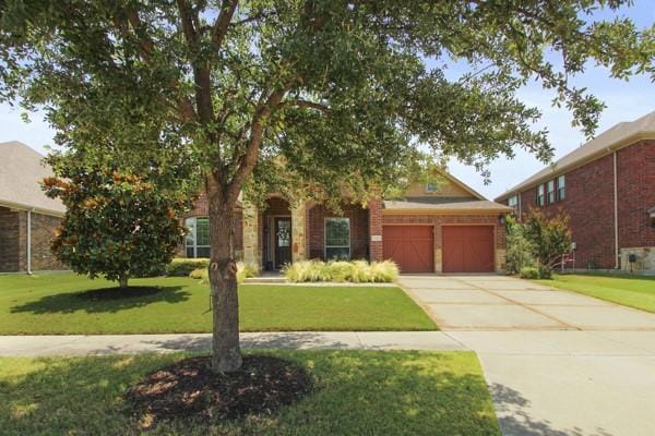 1165 Breakwater Dr, Frisco, TX 75036 - view of property hidden behind natural elements featuring a front yard, driveway, a garage, and brick siding