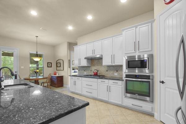 1165 Breakwater Dr, Frisco, TX 75036 - kitchen with appliances with stainless steel finishes, white cabinets, backsplash, recessed lighting, and under cabinet range hood
