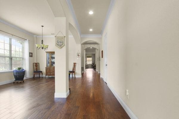 1165 Breakwater Dr, Frisco, TX 75036 - hallway with arched walkways, plenty of natural light, a chandelier, crown molding, and dark wood-style flooring