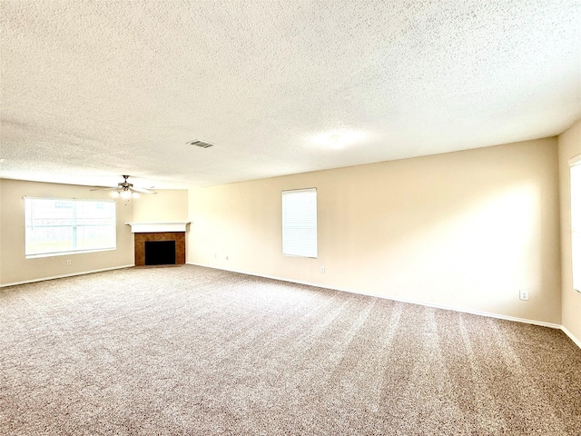 2024 Kings Forest Dr, Heartland, TX 75126 - unfurnished living room featuring a textured ceiling, carpet, a fireplace with flush hearth, and a ceiling fan