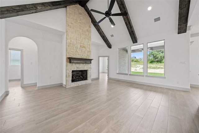 716 Burr Oak Ln, Weatherford, TX 76085 - unfurnished living room with a ceiling fan, beamed ceiling, light wood-style flooring, arched walkways, and high vaulted ceiling