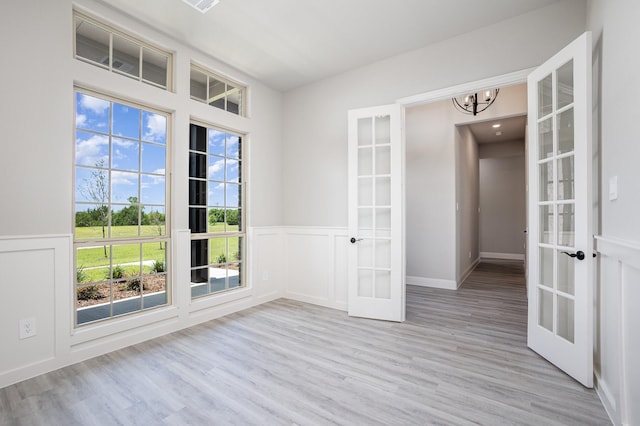 6821 Hayes Rd, Midlothian, TX 76065 - unfurnished room featuring french doors, wood finished floors, a chandelier, a wainscoted wall, and a decorative wall
