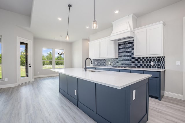 6821 Hayes Rd, Midlothian, TX 76065 - kitchen featuring premium range hood, stainless steel gas cooktop, light wood-style floors, decorative backsplash, and light countertops
