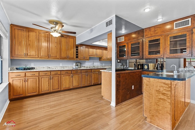 10030 Alondra St, Shreveport, LA 71115 - kitchen featuring brown cabinetry, light wood-style flooring, ceiling fan, and glass insert cabinets