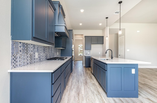 7050 Champion Rd, Midlothian, TX 76065 - kitchen featuring light wood-type flooring, backsplash, stainless steel gas stovetop, hanging light fixtures, and a kitchen island with sink