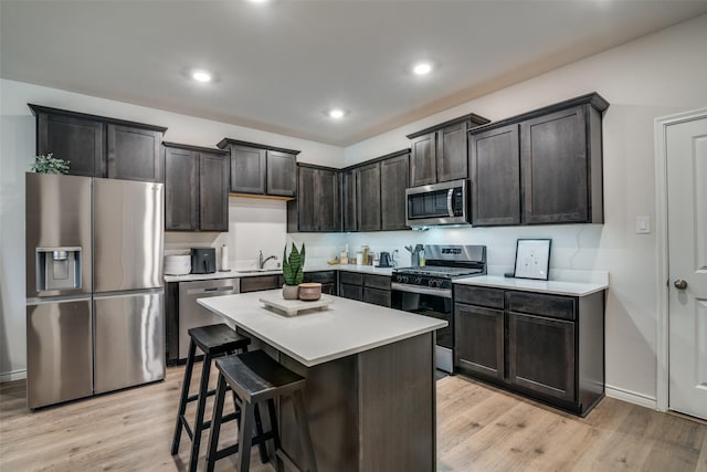 2016 Saddle Way, Mesquite, TX 75149 - kitchen with appliances with stainless steel finishes, light wood-type flooring, light countertops, a kitchen island, and a kitchen breakfast bar