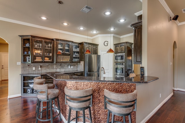 3231 Mccarver Ct, Midlothian, TX 76065 - kitchen with arched walkways, stainless steel appliances, dark brown cabinets, dark wood finished floors, and ornamental molding