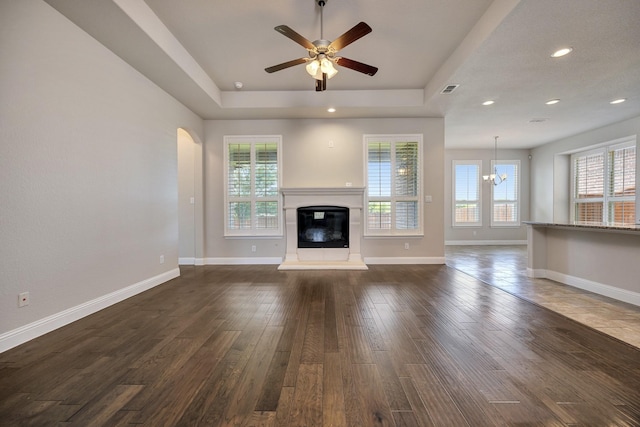 15005 Teasley Ave, Aledo, TX 76008 - unfurnished living room featuring a tray ceiling, a glass covered fireplace, a chandelier, ceiling fan, and dark wood-style flooring