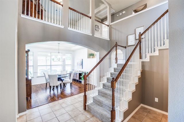 3504 Brookside Dr, Wylie, TX 75098 - staircase featuring tile patterned floors, arched walkways, a towering ceiling, and a chandelier