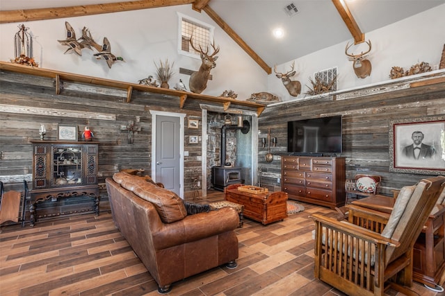 2473 Oil, City, Wilson, OK 73463 - living area featuring a wood stove, wooden walls, beam ceiling, wood finished floors, and high vaulted ceiling