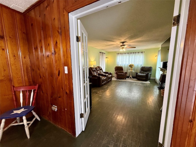 603 N Mesquite St, Hico, TX 76457 - hallway with dark wood-style flooring, a textured ceiling, and wood walls