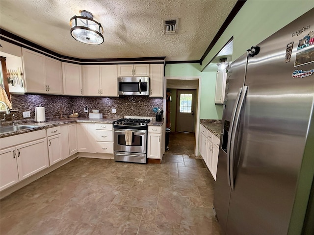 603 N Mesquite St, Hico, TX 76457 - kitchen featuring stainless steel appliances, backsplash, a textured ceiling, white cabinetry, and dark stone countertops
