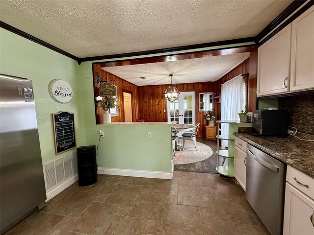 603 N Mesquite St, Hico, TX 76457 - kitchen featuring stainless steel appliances, a textured ceiling, wood walls, dark countertops, and a chandelier