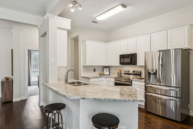 7105 Stoneridge Dr, Frisco, TX 75034 - kitchen with appliances with stainless steel finishes, a peninsula, a kitchen bar, and light stone countertops