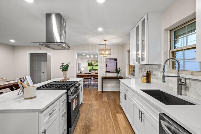 10017 Lanshire Dr, Dallas, TX 75238 - kitchen with gas range oven, stainless steel dishwasher, island range hood, white cabinetry, and light wood-style floors