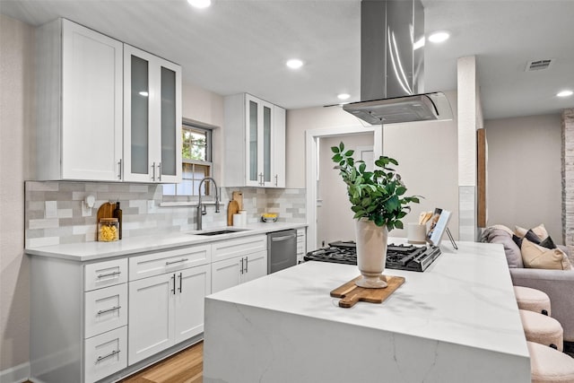 10017 Lanshire Dr, Dallas, TX 75238 - kitchen featuring island range hood, stainless steel dishwasher, gas cooktop, decorative backsplash, and white cabinetry