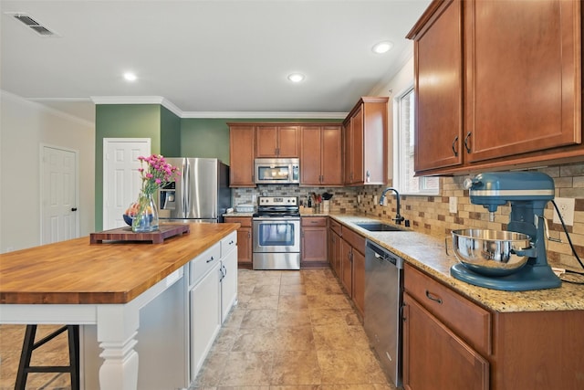 7732 Anatolian Way, Fort Worth, TX 76131 - kitchen with appliances with stainless steel finishes, wooden counters, backsplash, ornamental molding, and a breakfast bar area