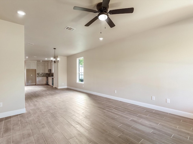 1510 N Wilhite St, Cleburne, TX 76031 - unfurnished living room featuring light wood-style floors, recessed lighting, a ceiling fan, and a chandelier