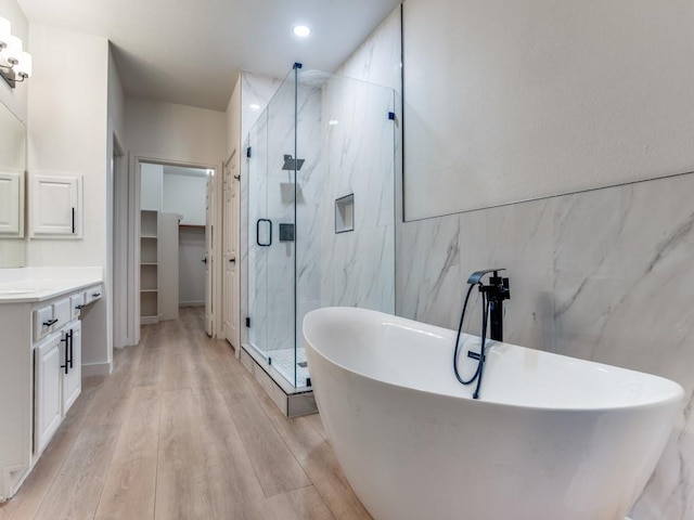 9816 Clocktower Ct, Plano, TX 75025 - full bathroom with vanity, a marble finish shower, tile walls, a freestanding bath, and wood finished floors