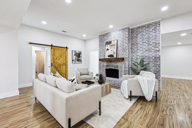 1722 Brighton Dr, Carrollton, TX 75007 - living room with a barn door, light wood finished floors, recessed lighting, and a brick fireplace