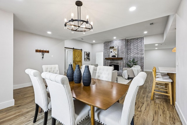 1722 Brighton Dr, Carrollton, TX 75007 - dining room with light wood-style floors, a chandelier, a barn door, recessed lighting, and a brick fireplace