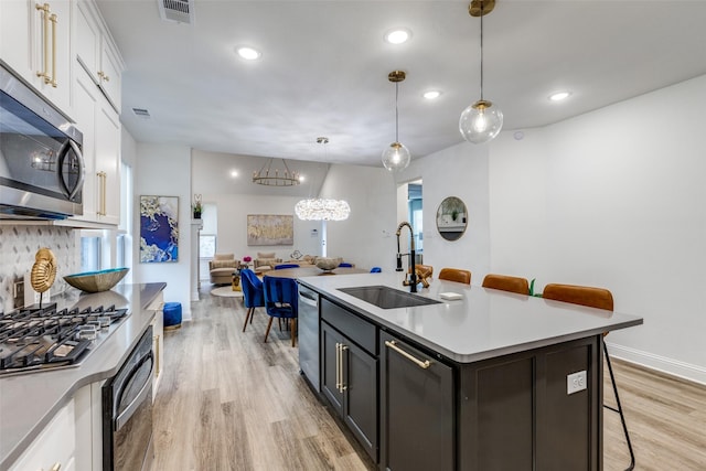2413 Latimer Mews, Celina, TX 75009 - kitchen with appliances with stainless steel finishes, light wood-type flooring, a breakfast bar, white cabinetry, and tasteful backsplash