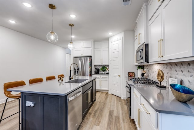 2413 Latimer Mews, Celina, TX 75009 - kitchen with stainless steel appliances, light wood finished floors, tasteful backsplash, white cabinetry, and decorative light fixtures