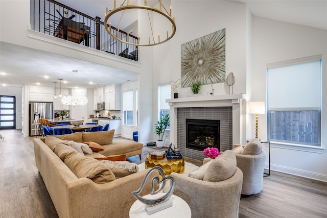 2413 Latimer Mews, Celina, TX 75009 - living room featuring a chandelier, wood finished floors, a tile fireplace, high vaulted ceiling, and healthy amount of natural light