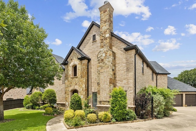 2157 Lookout Ct, Hurst, TX 76054 - view of home's exterior featuring a chimney, an attached garage, stone siding, driveway, and brick siding
