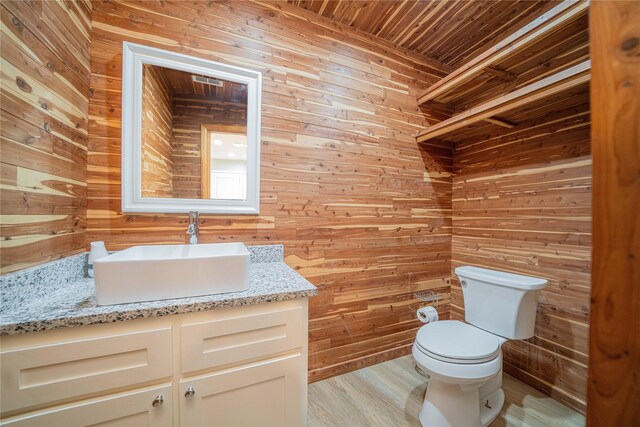812 E 1st, Hughes Springs, TX 75656 - half bathroom with wood walls, vanity, wooden ceiling, and wood finished floors