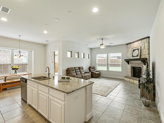 709 Providence, Wylie, TX 75098 - kitchen featuring dishwasher, a ceiling fan, a kitchen island with sink, a fireplace, and light stone countertops