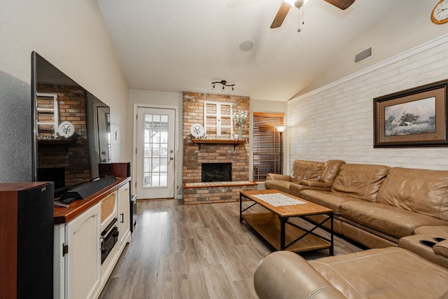 3615 7th St, Sachse, TX 75048 - living area with vaulted ceiling, a fireplace, a ceiling fan, and light wood-type flooring