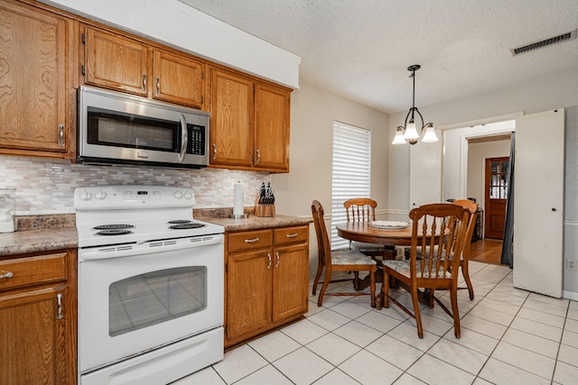 3615 7th St, Sachse, TX 75048 - kitchen with stainless steel microwave, white electric range oven, brown cabinets, decorative backsplash, and a textured ceiling