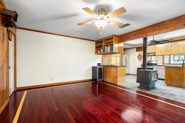 1933 E Hickory Hill Rd, Argyle, TX 76226 - unfurnished living room with a ceiling fan, light wood-style flooring, a wood stove, ornamental molding, and beverage cooler