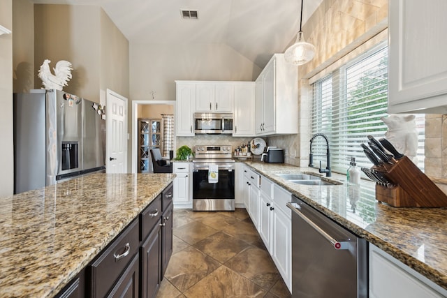 1608 Highland Oaks Dr, Keller, TX 76248 - kitchen with appliances with stainless steel finishes, white cabinetry, lofted ceiling, decorative backsplash, and light stone counters