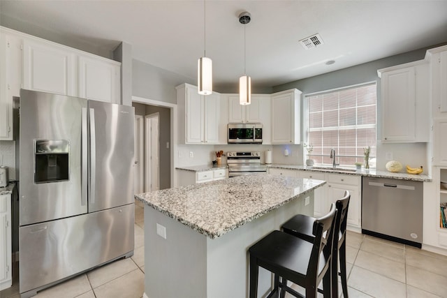 2525 Amber Ln, Flower Mound, TX 75028 - kitchen featuring stainless steel appliances, light tile patterned floors, a center island, white cabinets, and light stone countertops