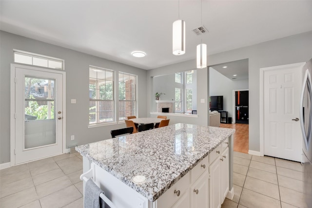 2525 Amber Ln, Flower Mound, TX 75028 - kitchen with light tile patterned flooring, light stone countertops, white cabinetry, and a center island