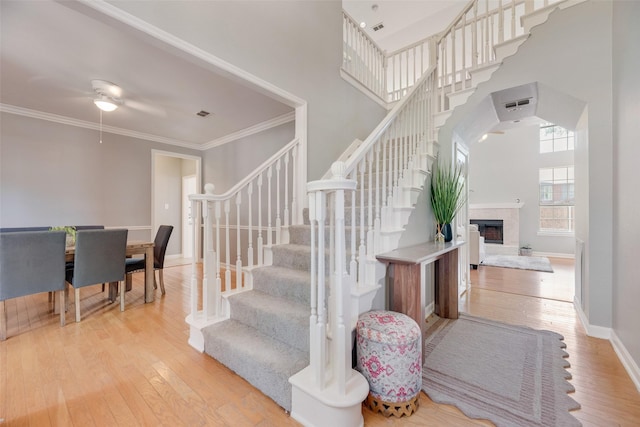 2525 Amber Ln, Flower Mound, TX 75028 - staircase with a high ceiling, hardwood / wood-style flooring, a ceiling fan, ornamental molding, and a fireplace with raised hearth