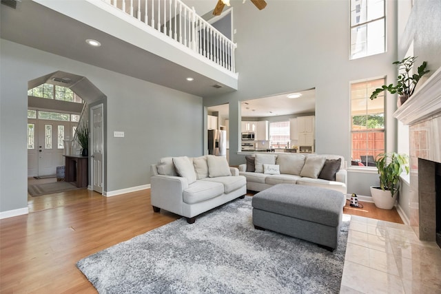 2525 Amber Ln, Flower Mound, TX 75028 - living area with a towering ceiling, light wood finished floors, a ceiling fan, a tile fireplace, and recessed lighting