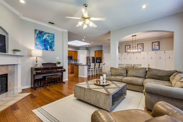 5628 Vineyard Ln, Mckinney, TX 75070 - living area with ceiling fan, a tiled fireplace, light wood-style floors, recessed lighting, and ornamental molding