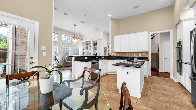 6740 Magnum Dr, Plano, TX 75024 - kitchen with dark countertops, a peninsula, white cabinetry, a kitchen island, and recessed lighting