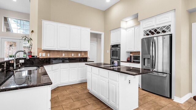 6740 Magnum Dr, Plano, TX 75024 - kitchen with appliances with stainless steel finishes, a towering ceiling, dark stone counters, light tile patterned floors, and decorative backsplash