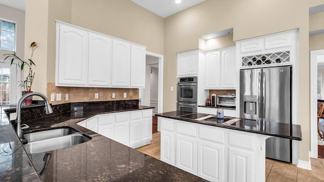 6740 Magnum Dr, Plano, TX 75024 - kitchen with stainless steel appliances, backsplash, dark stone counters, a high ceiling, and white cabinetry