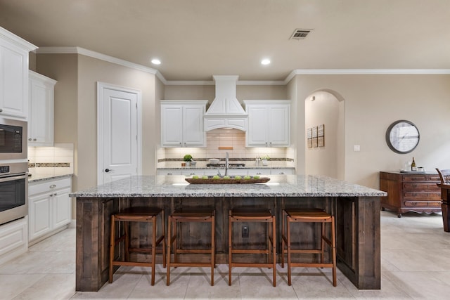 8240 Odell St, North Richland Hills, TX 76182 - kitchen featuring appliances with stainless steel finishes, custom range hood, tasteful backsplash, light stone countertops, and crown molding