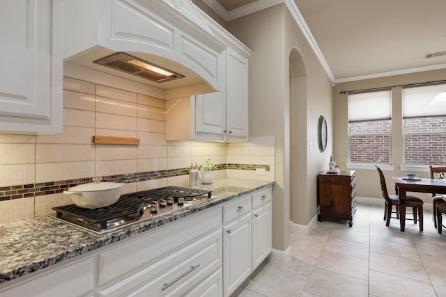 8240 Odell St, North Richland Hills, TX 76182 - kitchen with stainless steel gas stovetop, light stone counters, backsplash, white cabinets, and ornamental molding