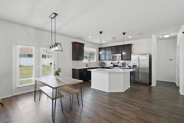 9009 Benevolent Ct, Providence Village, TX 76227 - kitchen featuring appliances with stainless steel finishes, backsplash, a center island, light countertops, and dark wood finished floors