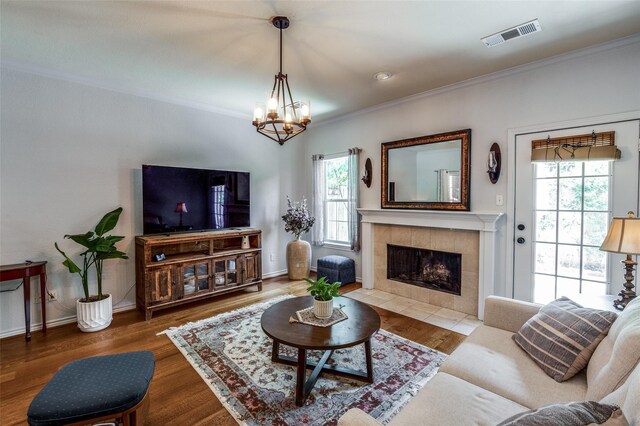 17342 Remington Park Pl, Dallas, TX 75252 - living room with a chandelier, crown molding, a tiled fireplace, and wood finished floors